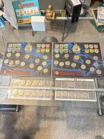 Two Canada 125 display boards and two plastic album pages with coins on glass table