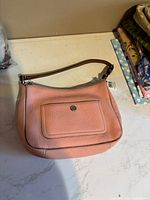 Front view of Coach pink leather hobo bag with front pocket and tag