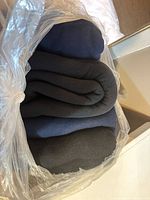 Rolled navy, charcoal and black fleece panels inside clear plastic bag