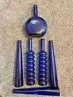 All six cobalt blue blown glass bud vases arranged on carpet showing shapes and condition