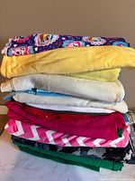 Stack of approx ten folded knit fabrics showing variety of colors and prints