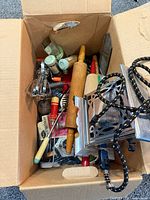 Top view of cardboard box containing mixed vintage kitchen utensils and tools