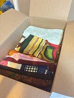 Open box showing multiple folded cotton fabric pieces of varied colours and prints