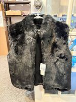 Front view of black faux fur vest on hanger