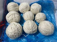 Nine off-white yarn balls on blue plastic