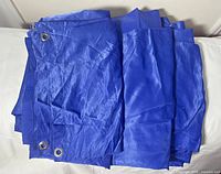 Stack of folded blue drape panels showing grommets