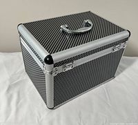 Three-quarter exterior view showing carbon pattern panels, aluminum frame, chrome handle