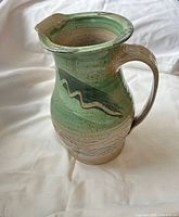 Front view of green and beige ceramic pitcher
