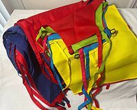 Pile of colourful aprons showing red, navy and yellow pieces with straps
