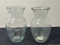 Two clear glass vases upright on black cloth