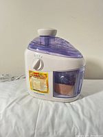 Front angled view of Hamilton Beach juicer showing control dial, lid, and branding sticker