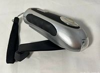 Side view showing folded crank handle extended from silver and black flashlight