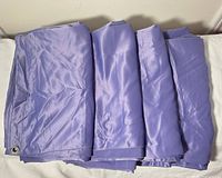 Four folded purple curtain panels laid side by side