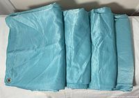 Folded turquoise drapery panels showing fabric and grommet edge