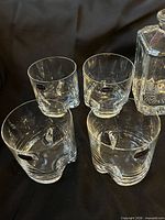 Four whiskey tumblers and corner of decanter showing labels