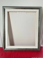 Front view of empty silver-grey wooden frame with mat