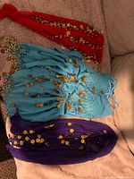 Red, blue and purple coin hip scarves displayed on surface