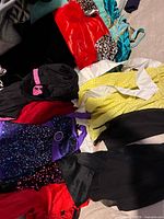 Pile of assorted costumes showing sequins, yellow textured top and various colours