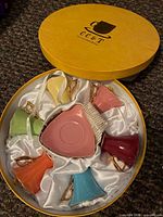Box interior showing six coloured cups and saucers