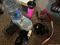 All items laid out: water dispenser, travel bottle, bark control devices, collars, harness