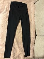 Full view of black leggings laid flat showing front and waistband