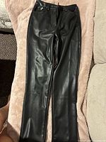 Front view of black faux leather pants laid flat