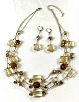 Full view of three-strand necklace with matching earrings on white background