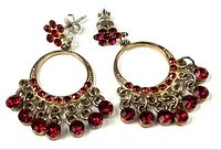 Full view of both gold-tone earrings with red stones