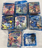 All eight sealed toy packages laid out, seven Legion Happy Meal bags and one TMNT Stunt Strikers bag