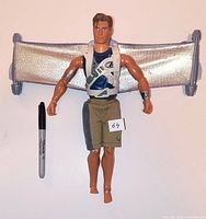 Front view of Max Steel figure with attached silver glider wing and marker for scale