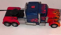 Left side view of Optimus Prime truck showing flame decals, exhaust stacks and rear battery compartment