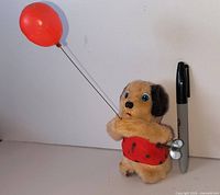 Wind-up dog toy beside marker for scale