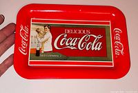Front of rectangular Coca-Cola tip tray with red border and vintage advertisement graphic