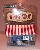 Front view of sealed Greenlight The Hobby Shop Series 12 package containing 1:64 scale 2001 Jeep Cherokee Sport and race car driver figure