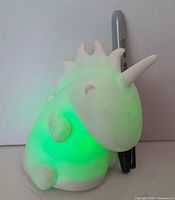 Unicorn night light illuminated green with Sharpie for scale