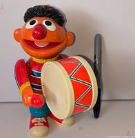 Front view of Ernie wind-up drummer toy with drum and drumstick visible