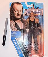 Front view of sealed WWE WrestleMania Undertaker figure with Sharpie for scale