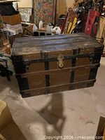 Front view of antique steamer trunk showing metal lock and bands