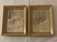 Front view of both framed prints showing fox and rabbit images, oak frames