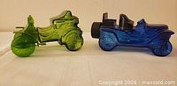 Side view of both green Haynes-Apperson and blue Stanley Steamer glass car bottles