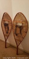 Full view of both snowshoes leaning against wall