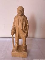 Front view of carved wood elderly man with cane on rectangular base