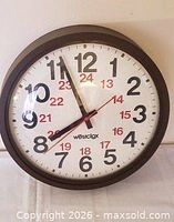 Front view of Westclox wall clock showing brown frame, dual-time numerals, hands, and lens