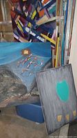 Three of the paintings: multicolour geometric, fish over landscape, teal on grey