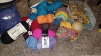 Group shot of assorted yarn skeins, cakes, balls and craft bag on carpet