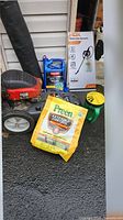 Group shot of trimmer, chemical containers, sprayer box, hand spreader