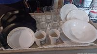 Tray with entire lot: black plates, clear glasses, mugs, white plates and bowls