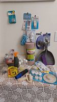 Overall view showing duster, hooks on wall, shelf liner roll, dustpan set and assorted tabletop items