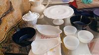 Group shot of entire lot showing cake stand, pitcher, lidded dish, pear dish, oval dish, three white bowls and two blue bowls