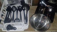 Overall lot: dish rack holding nylon utensils, flatware in tray, stainless colander beside